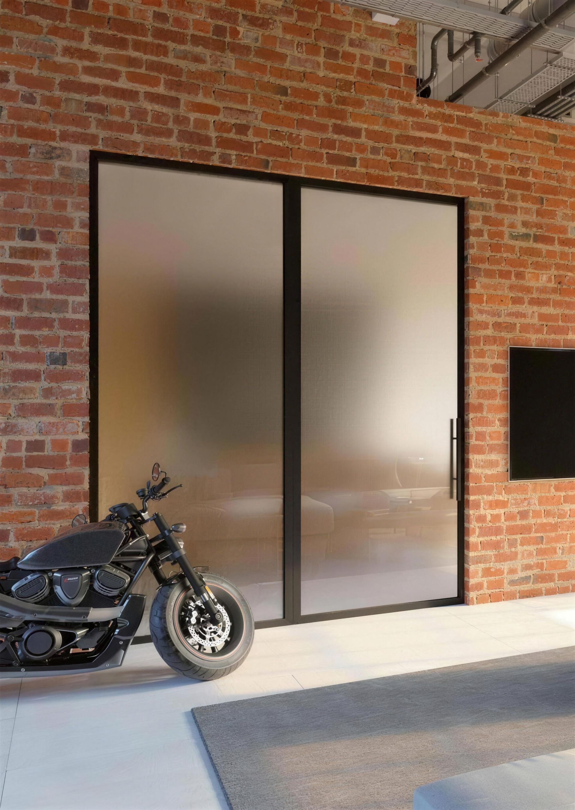 Framework Pivottür mit satiniertem Glas vor Backsteinwand